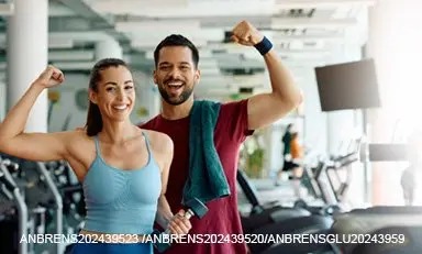 Casal adulto na academia, sorrindo, mostrando seus músculos