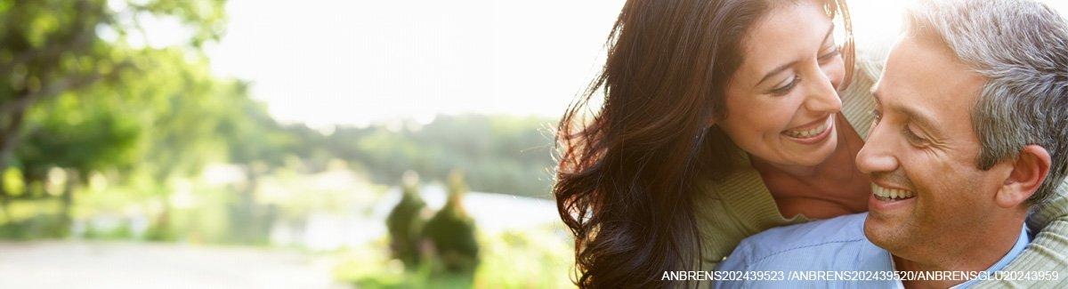 Casal de adultos abraçados ao ar livre, sorrindo