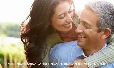 Casal de adultos abraçados ao ar livre, sorrindo