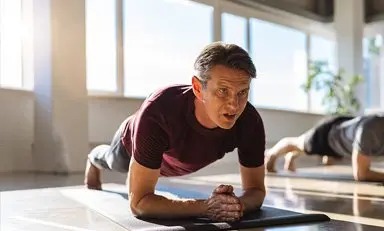 Adultos em posição de prancha, exercitando o corpo.