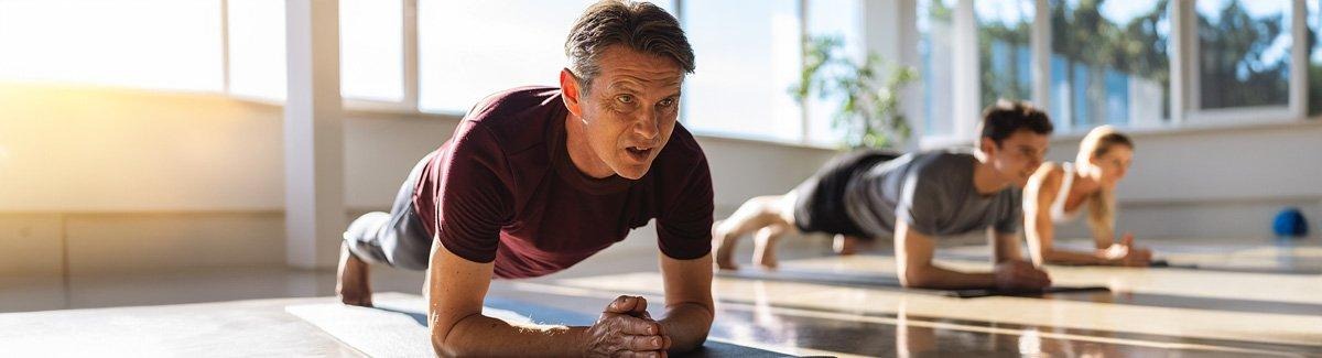 Adultos em posição de prancha, exercitando o corpo.