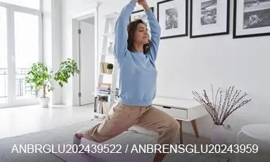 Mulher jovem em um apartamento iluminado, exercitando-se, respirando profundamente, transmitindo saúde, equilíbrio e serenidade.