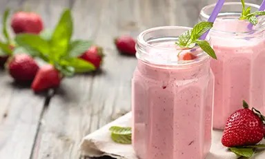 Shake de morango com Glucerna sabor baunilha em copo sobre fundo de madeira com morangos