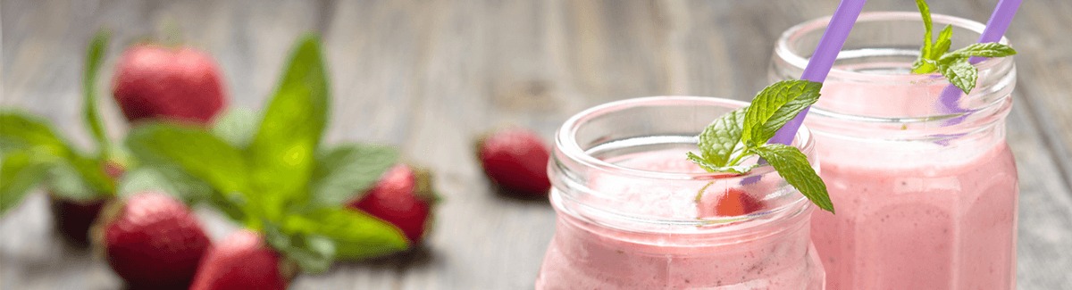 Shake de morango com Glucerna sabor baunilha em copo sobre fundo de madeira com morangos