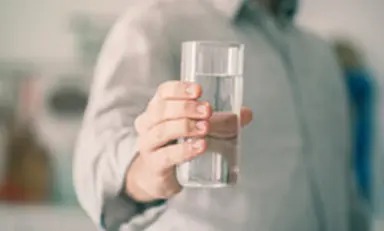 Homem segurando um copo de água