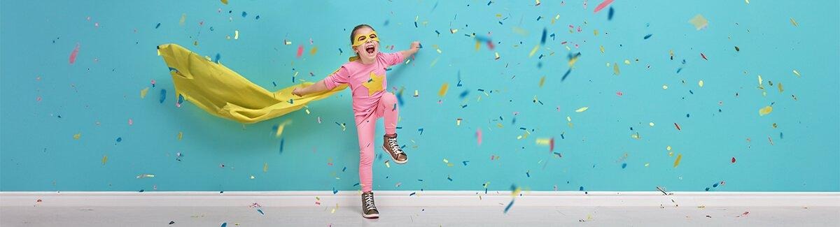 Menina com rabos de cavalo e suéter amarelo lendo um livro ao lado de um adulto