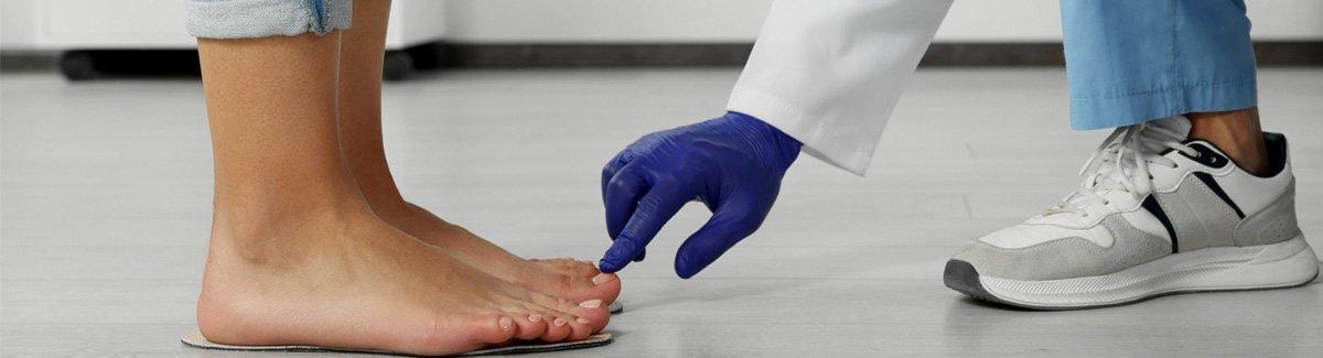 Médico tocando um dedo do pé de uma paciente.