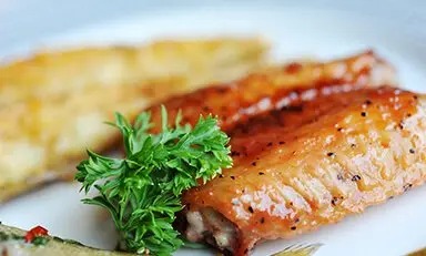 Filé de salmão cozido com pele, acompanhado de uma fatia de limão.