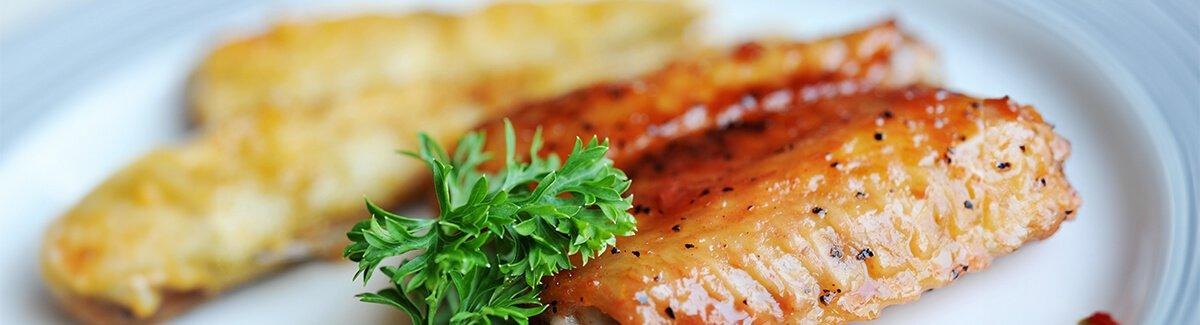 Filé de salmão cozido com pele, acompanhado de uma fatia de limão.