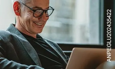Homem adulto sorrindo em frente ao computador